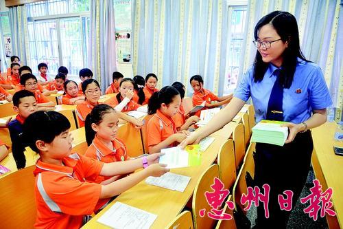 龙门县人民检察院干警向学生派发法治教育宣传资料。